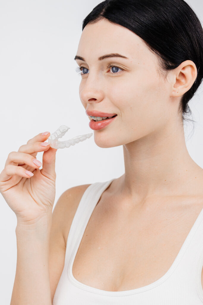 Woman wears transparent orthodontic trainer. Concept of teeth correction and beautiful smile.