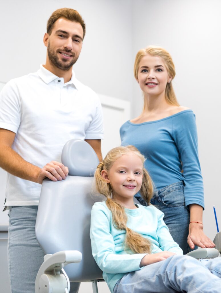 happy young family looking at camera at dentist office